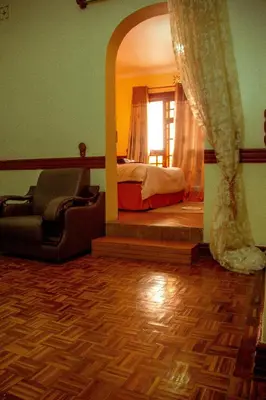 a bedroom with a bed and a chair and a mirror at The Charity Hotel International in Arusha