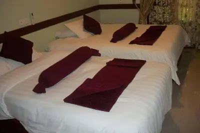 two beds with towels and pillows on them at The Charity Hotel International in Arusha