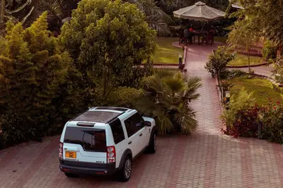 a white suv parked on a brick driveway at The Charity Hotel International in Arusha