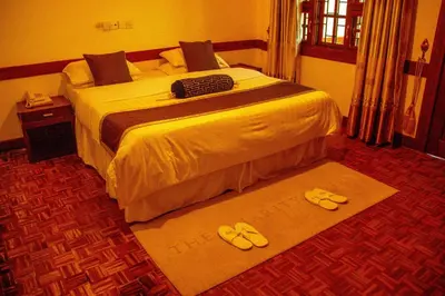 a hotel room with a bed with slippers on the floor at The Charity Hotel International in Arusha
