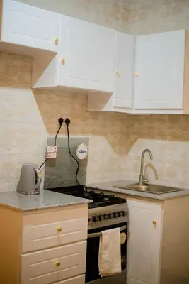 a kitchen with white cabinets and a stove and a sink at Hecasa Apartments in Arusha