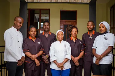 a group of men and women standing in a room at Hecasa Apartments in Arusha