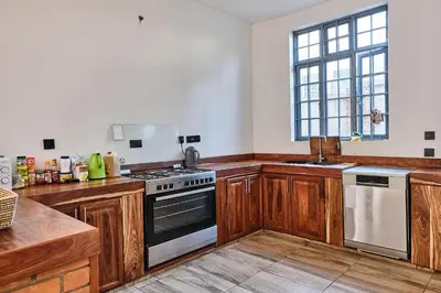 a kitchen with wooden cabinets and a stove top oven at Elmitho House in Arusha