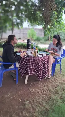 a man and woman sitting at a picnic table at Lasts minute lodge in Boma la Ngombe