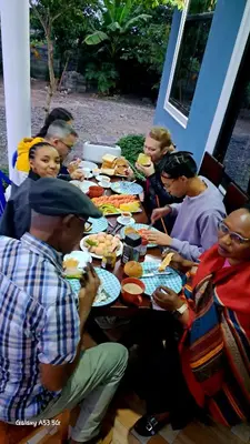 a group of people sitting around a table eating food at Lasts minute lodge in Boma la Ngombe