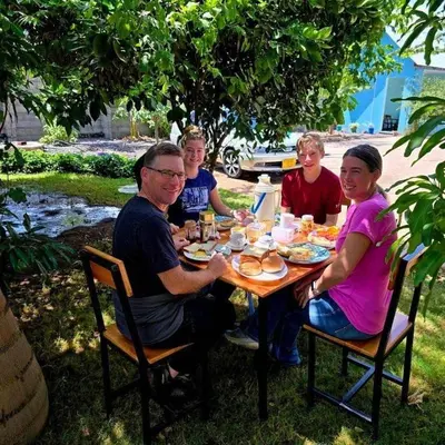 a group of people sitting around a table eating food at Lasts minute lodge in Boma la Ngombe