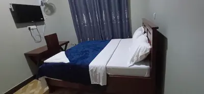 a bedroom with a bed with a blue blanket and a tv at Lasts minute lodge in Boma la Ngombe