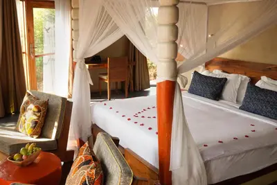 a bedroom with two beds with a canopy bed at Suricata Boma Lodge in Mto wa Mbu