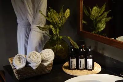 a bathroom counter with towels and bottles of wine at Suricata Boma Lodge in Mto wa Mbu