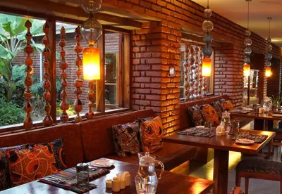 a restaurant with tables and chairs and a brick wall at Suricata Boma Lodge in Mto wa Mbu