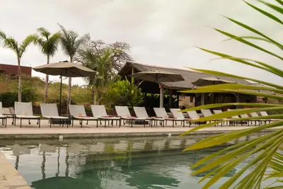 a group of chairs and umbrellas next to a pool at Suricata Boma Lodge in Mto wa Mbu
