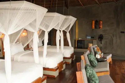 a room with four beds with white canopy beds at Suricata Boma Lodge in Mto wa Mbu