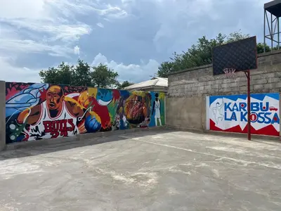 a wall with paintings on it with a basketball court at karibu la kossa in Tuvaila