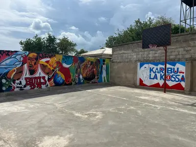 a basketball court with graffiti on the wall at karibu la kossa in Tuvaila