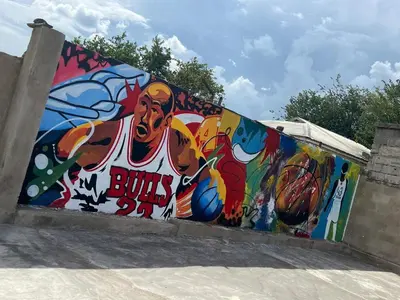 a wall with a painting of a basketball player on it at karibu la kossa in Tuvaila