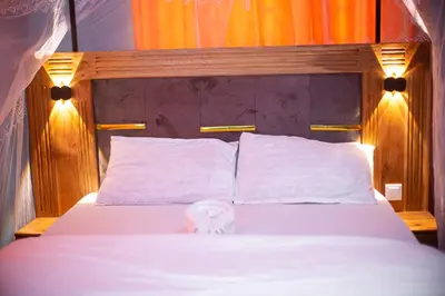 a bedroom with a bed with white sheets and pillows at karibu la kossa in Tuvaila