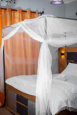 a bed with a mosquito net on top of it at karibu la kossa in Tuvaila