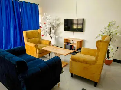 a living room with a couch and two chairs and a tv at karibu la kossa in Tuvaila