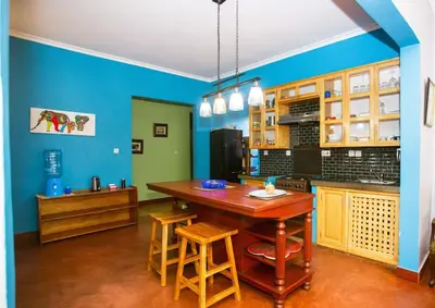 a kitchen with blue walls and a wooden table and chairs at Rau River House - Moshi in Msaranga