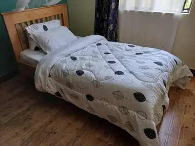 a bed with a comforter and pillows on it at Rau River House - Moshi in Msaranga
