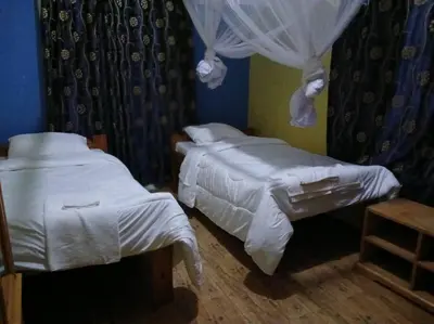 a bedroom with two beds with white sheets and curtains at Rau River House - Moshi in Msaranga