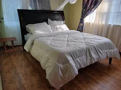 a bedroom with a large white bed with a window at Rau River House - Moshi in Msaranga