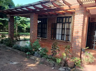 a brick house with a pergola and some plants at Rau River House - Moshi in Msaranga