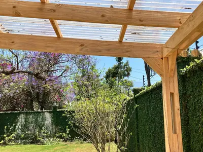 a wooden pergola with a garden in the background at Allamanda House Meru in Arusha