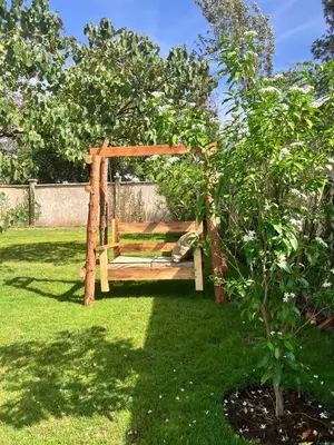 a wooden swing in a garden with a tree at Allamanda House Meru in Arusha