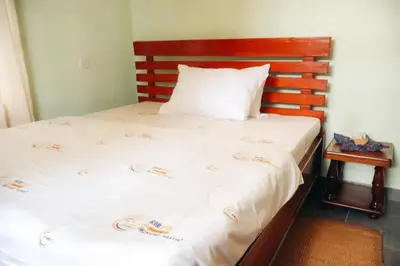 a bedroom with a bed with a wooden headboard at Mesa, Mama Ket Homes Arusha in Arusha