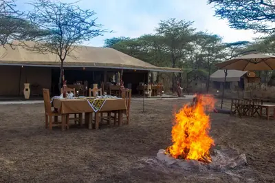a campfire in front of a table and a tent at Africa Safari Serengeti Kusini in Serengeti National Park