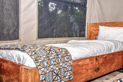 a bedroom with a wooden bed with a zebra in a window at Africa Safari Rift Valley Camping in Magara