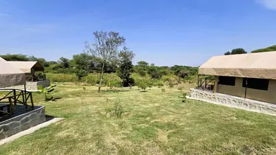 a building with a grass yard next to a field at Africa Safari Rift Valley Camping in Magara