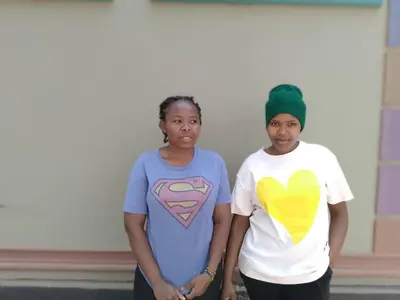 two women standing next to each other in front of a building at Dangote Farm House Eyasi in Mangola