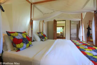 a bedroom with a canopy bed with colorful pillows at Marangu Hotel in Marangu
