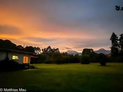 a house in a field with a sunset in the background at Marangu Hotel in Marangu