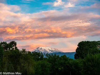a snow covered mountain under a cloudy sky at Marangu Hotel in Marangu