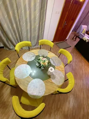 a dining room table with yellow chairs and a table with flowers at SandS Escape in Arusha