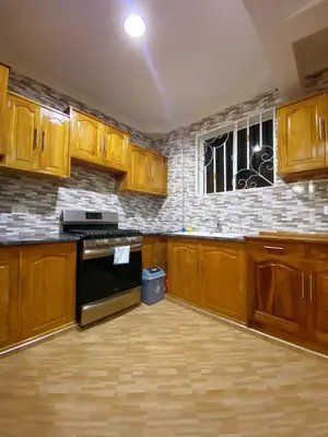 an empty kitchen with wooden cabinets and a window at SandS Escape in Arusha