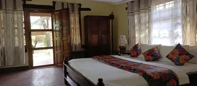 a bedroom with a bed and a window and a door at Kilimanjaro Lodge Cabins in Moshi