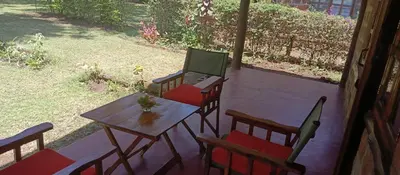 a patio with a table and chairs with a laptop on it at Kilimanjaro Lodge Cabins in Moshi