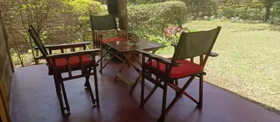 three chairs and a table on a porch at Kilimanjaro Lodge Cabins in Moshi