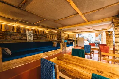 a dining room with a blue couch and a wooden table at Samora River Lodge in Kioga