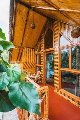 a wooden house with a large window and a chair at Samora River Lodge in Kioga