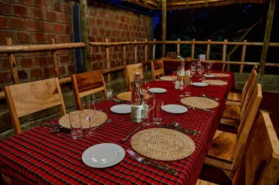a table with plates and glasses on a red table cloth at Samora River Lodge in Kioga