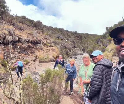 a group of people walking on a mountain trail at House of West Kili in Bondeni Boloti