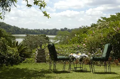 two chairs and a table in the grass near a lake at Arusha Serena Hotel in Nkoanrua