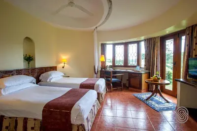 a hotel room with two beds and a desk at Arusha Serena Hotel in Nkoanrua