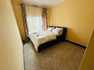a small bedroom with a bed with a window at Mlay Home in Arusha