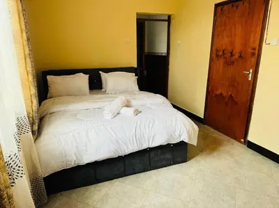 a bedroom with a large bed with white sheets at Mlay Home in Arusha